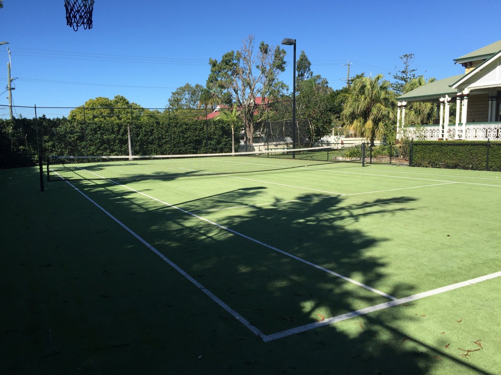 Tennis Court with a Basketball Hoop and a House in the Background — Queensland, Australia — Jordin Sports Constructions