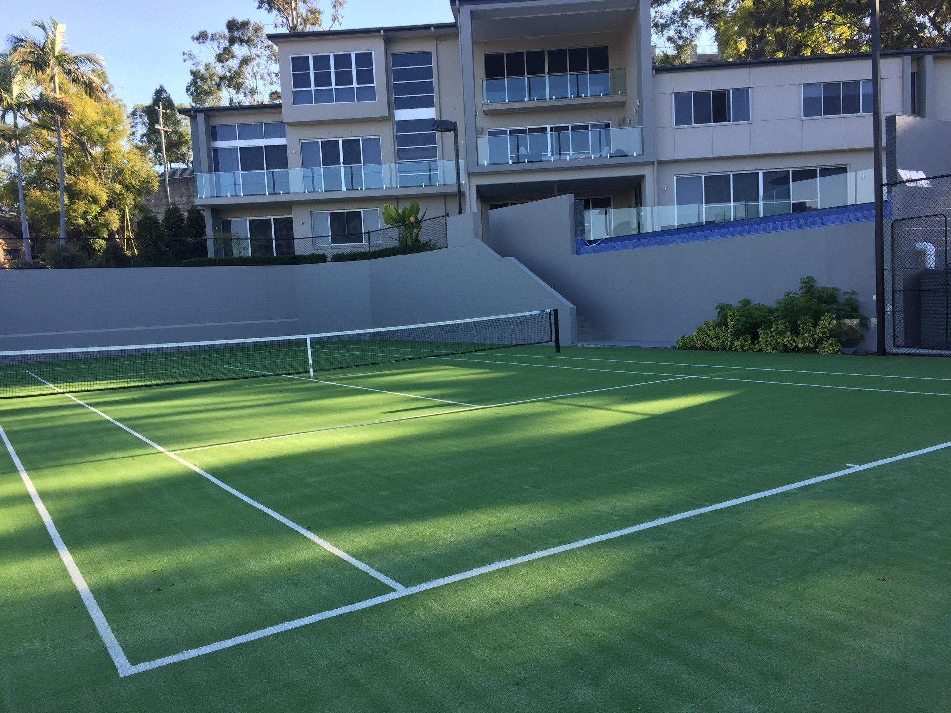 Tennis Court with a Large Building in the Background — Queensland, Australia — Jordin Sports Constructions