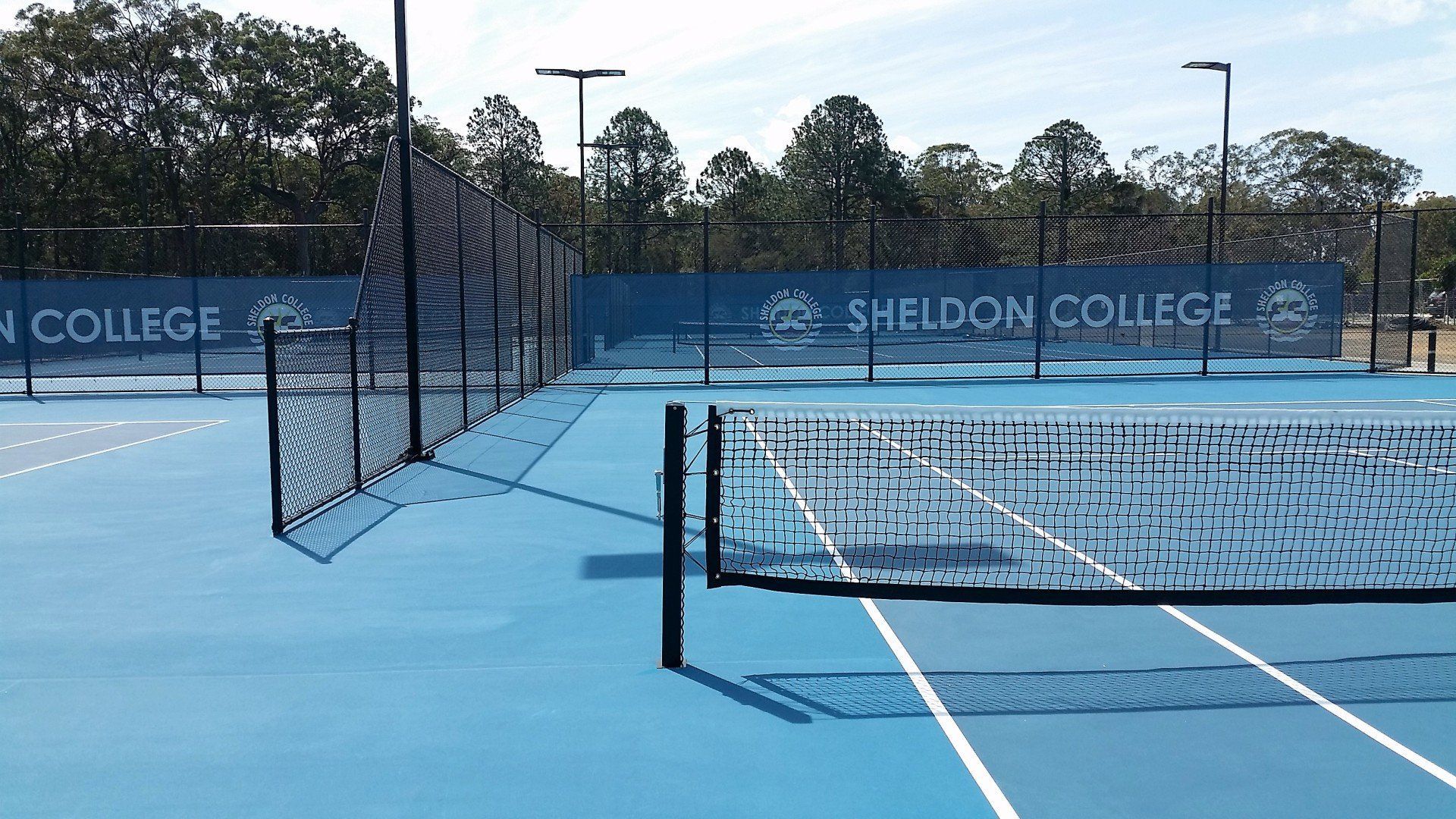 Tennis Court with a Banner that says Sheldon College — Queensland, Australia — Jordin Sports Constructions