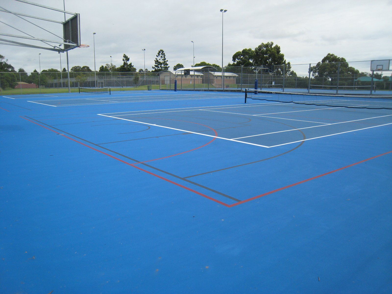 Blue Tennis Court with a Basketball Hoop in the Background — Queensland, Australia — Jordin Sports Constructions