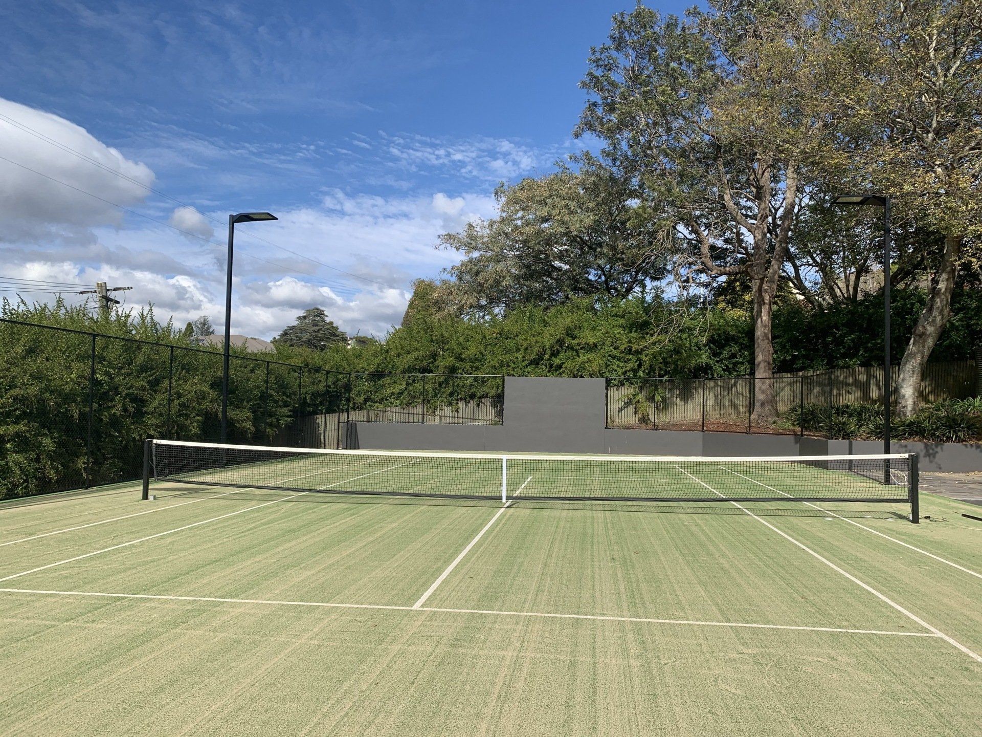 Tennis Court with a Net and Trees in the Background — Queensland, Australia — Jordin Sports Constructions
