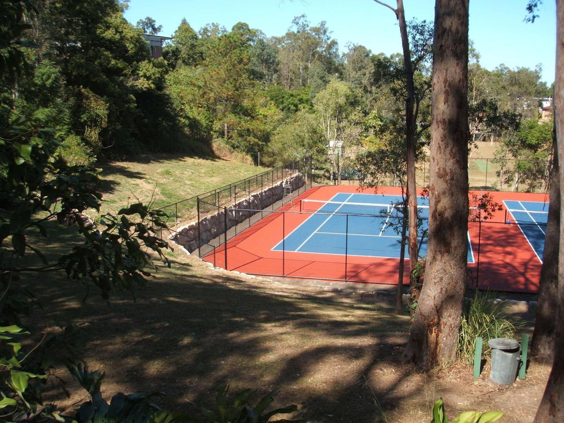 A Blue and Red Tennis Court Surrounded by Trees — Queensland, Australia — Jordin Sports Constructions