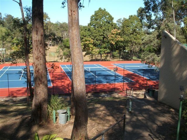 Tennis Court Surrounded by Trees on a Sunny Day — Queensland, Australia — Jordin Sports Constructions