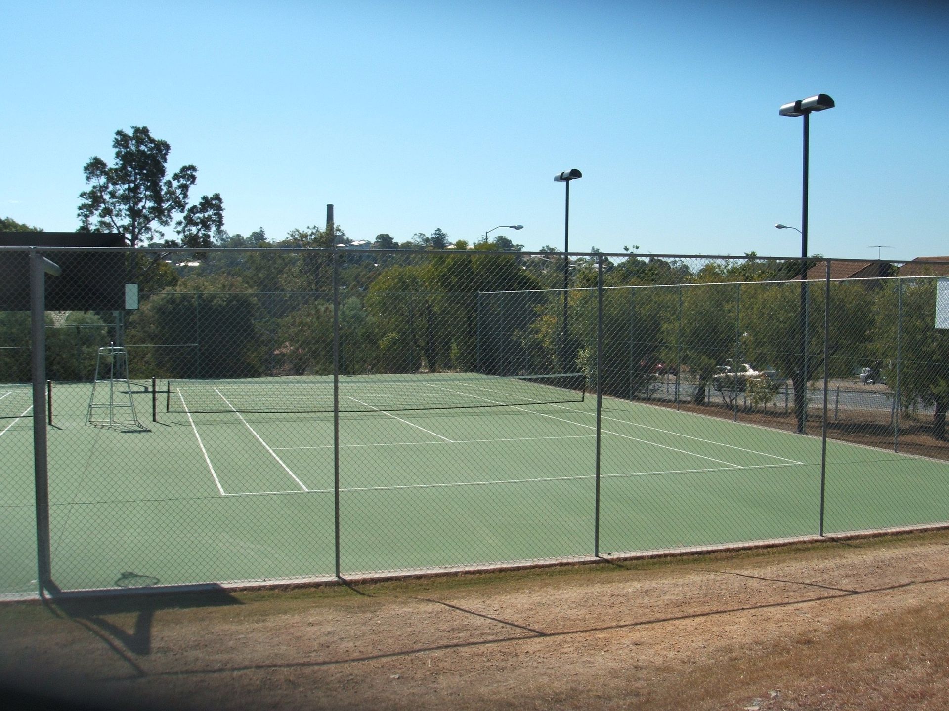 A Tennis Court with a Fence and Trees in the Background — Queensland, Australia — Jordin Sports Constructions