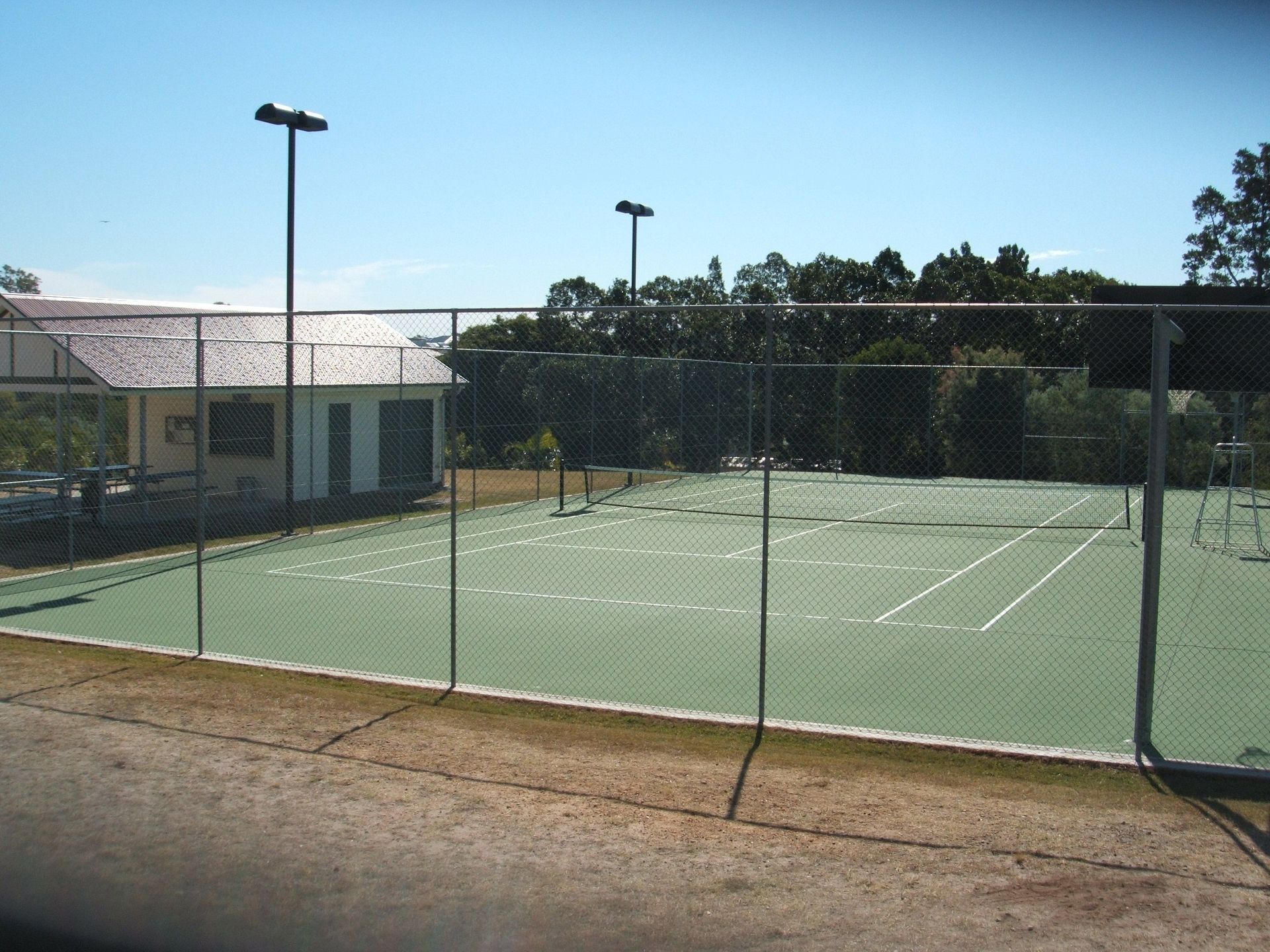 Tennis Court with a Fence and a Building in the Background — Queensland, Australia — Jordin Sports Constructions