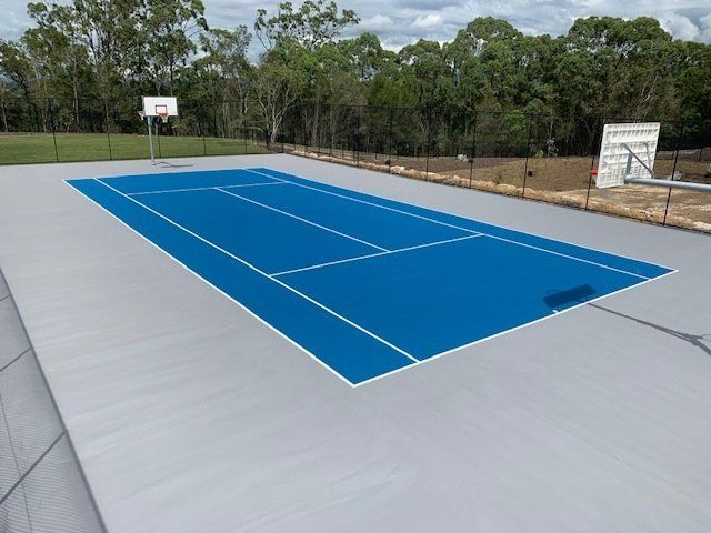 A Blue Tennis Court with a Basketball Hoop in the Background — Queensland, Australia — Jordin Sports Constructions