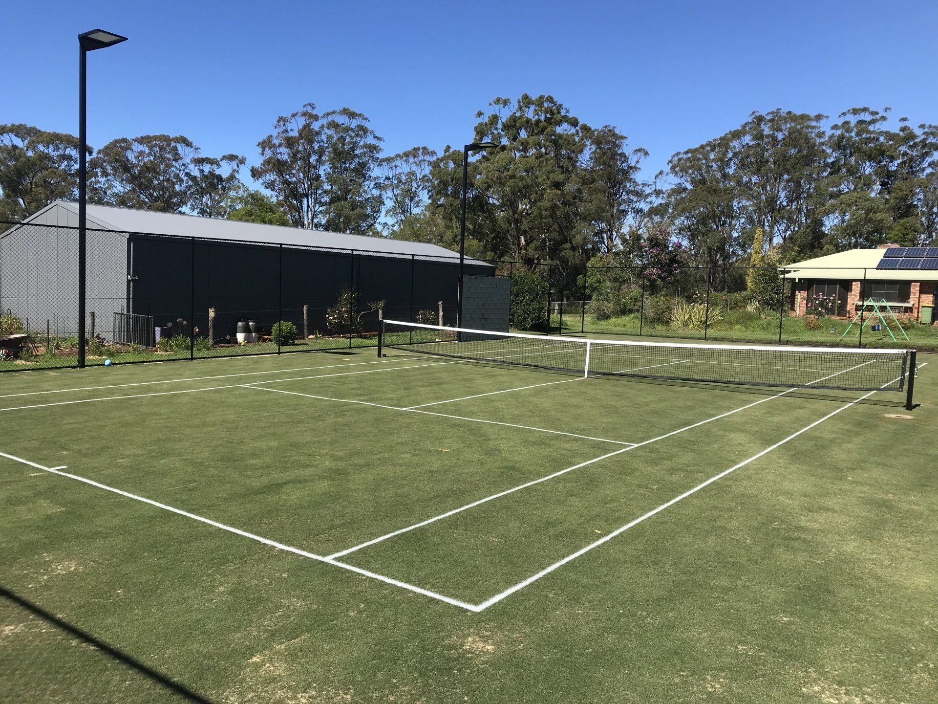 Tennis Court with a House in the Background — Queensland, Australia — Jordin Sports Constructions