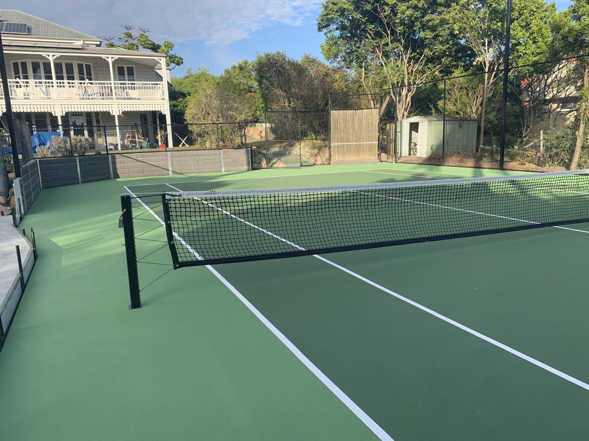 Tennis Court with a Net and a House in the Background — Queensland, Australia — Jordin Sports Constructions