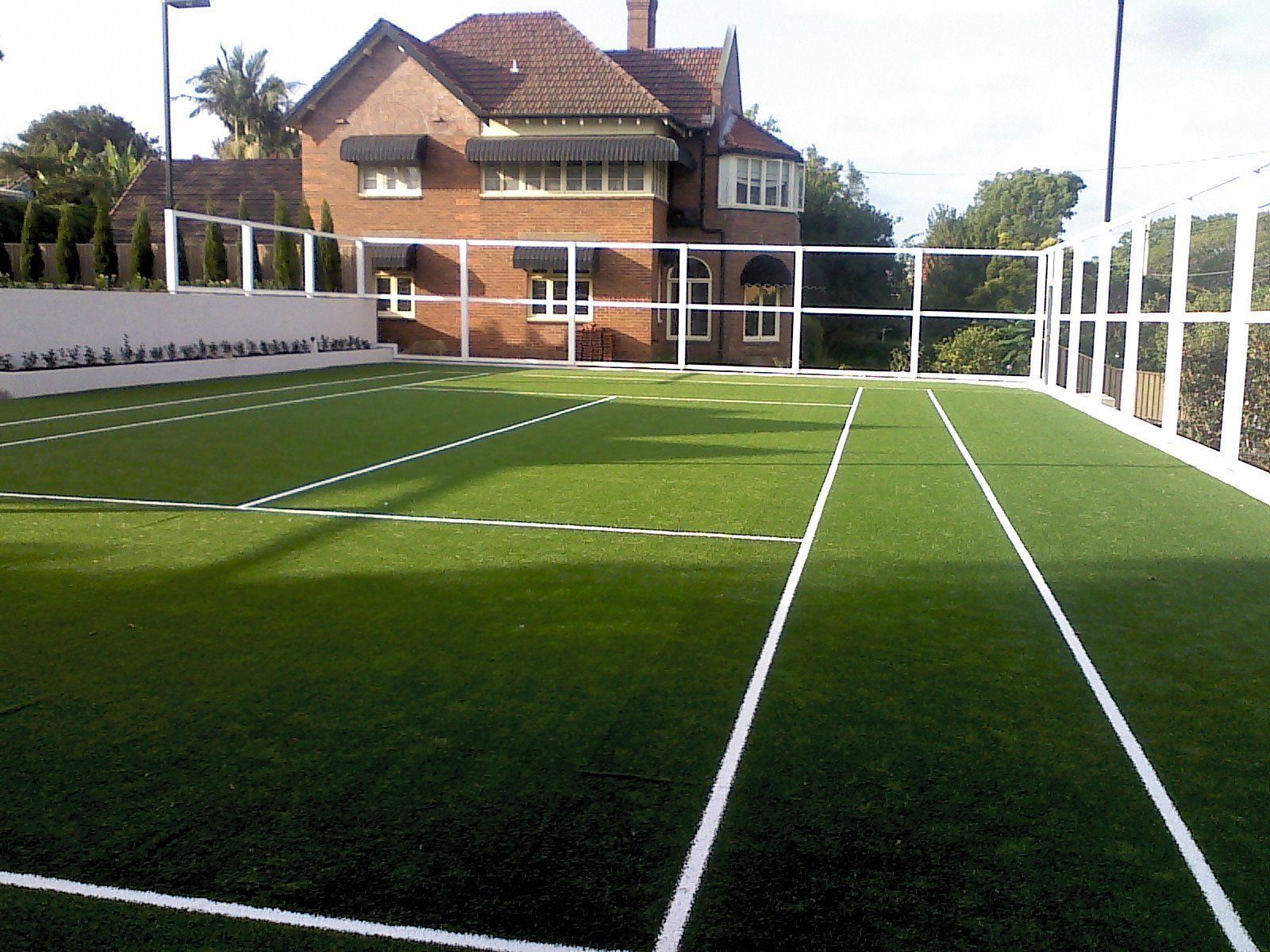 A Tennis Court with a House in the Background — Queensland, Australia — Jordin Sports Constructions