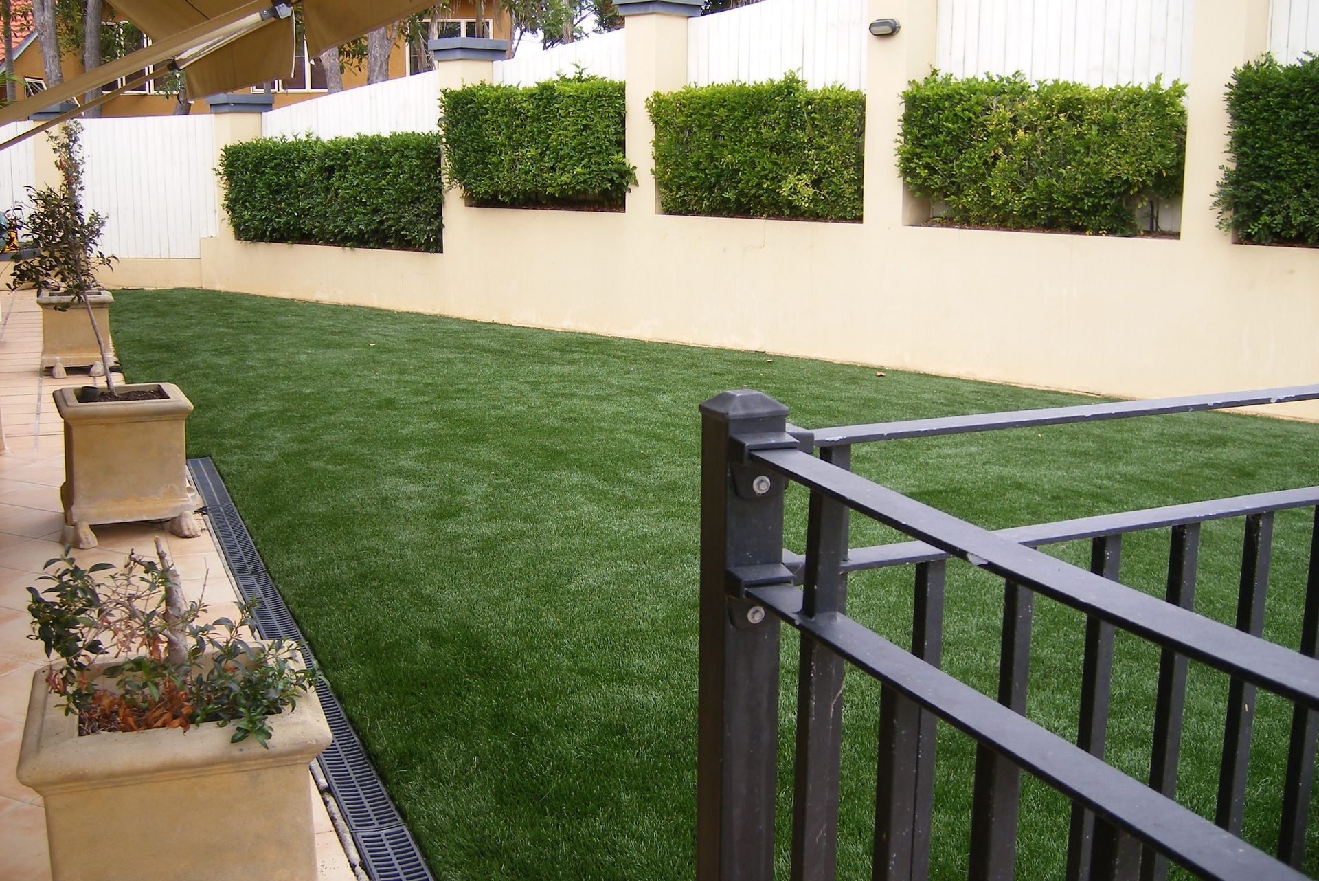A Fence Surrounds a Lush Green Lawn With Potted Plants — Queensland, Australia — Jordin Sports Constructions