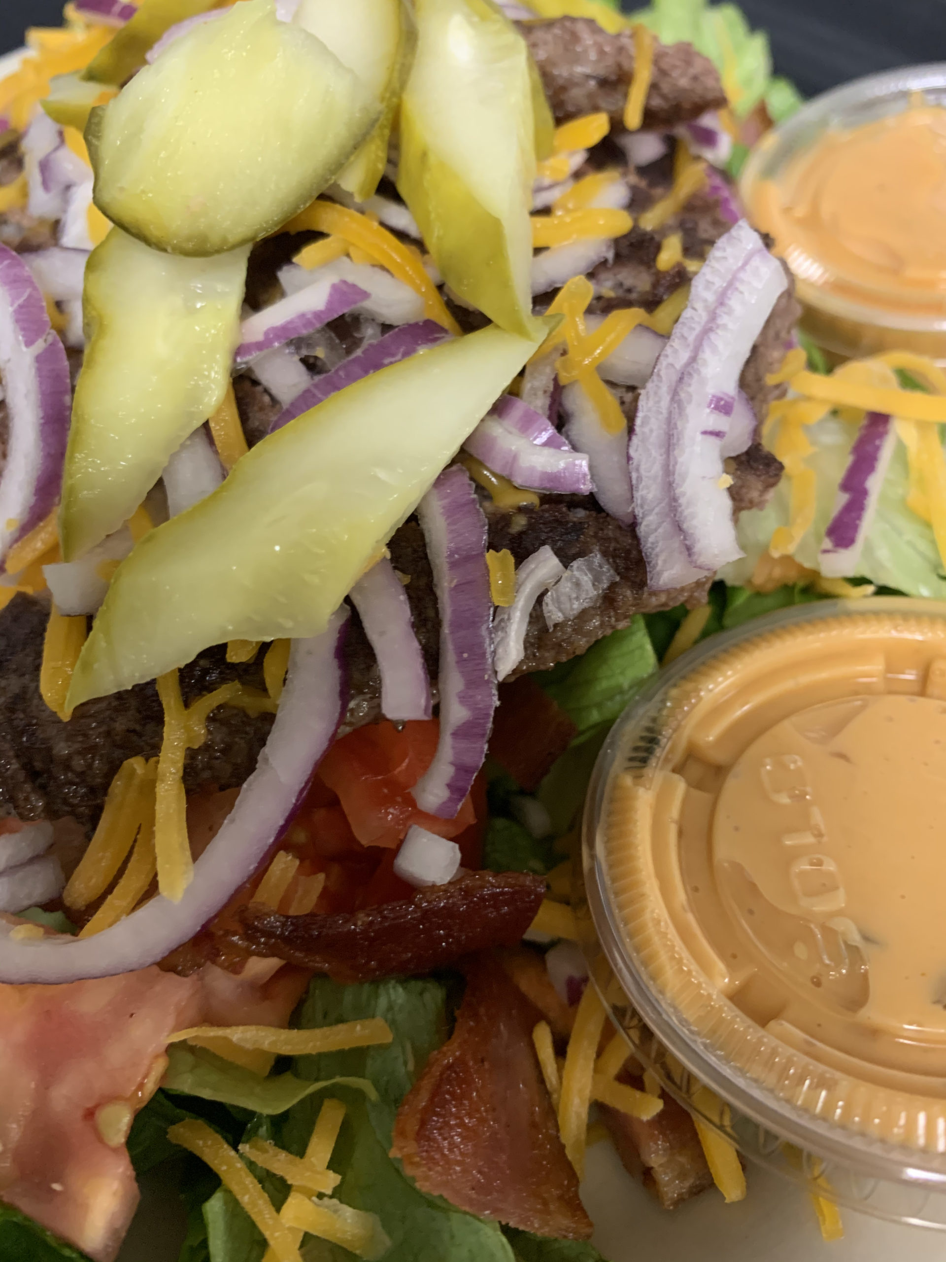 A close up of a salad with a dipping sauce on the side