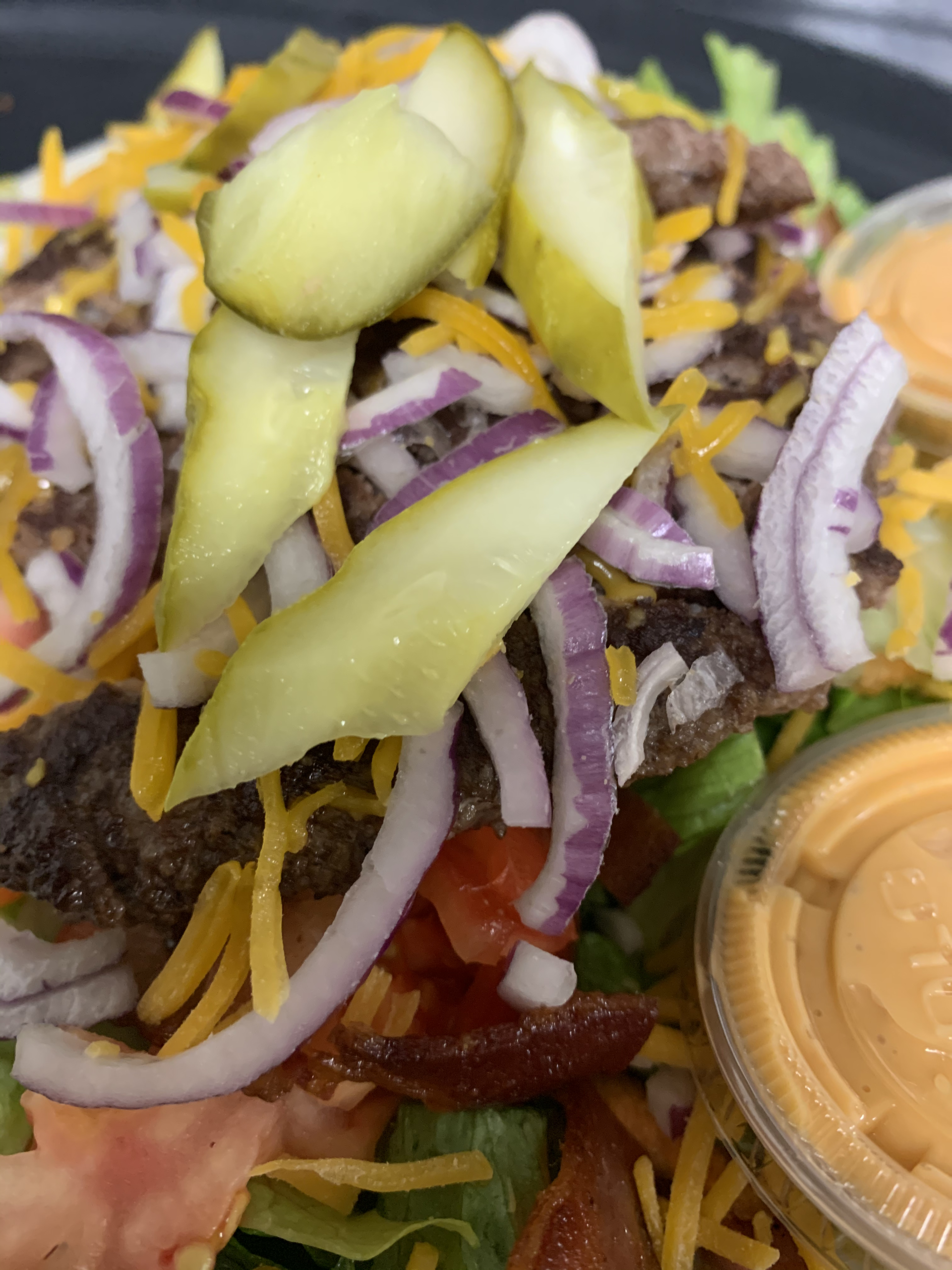 A close up of a salad with a container of dressing on the side.