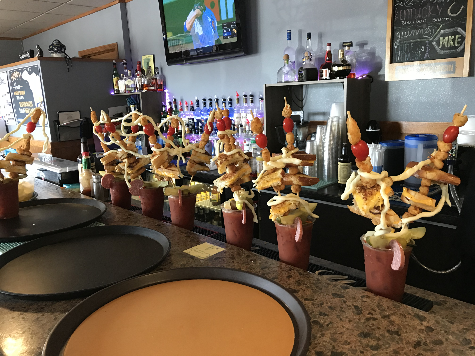 A bar with a lot of food on the counter and a tv on the wall.