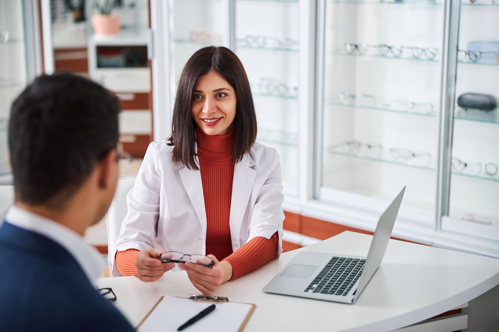 A female optometrist is showing the eyewear to her client.