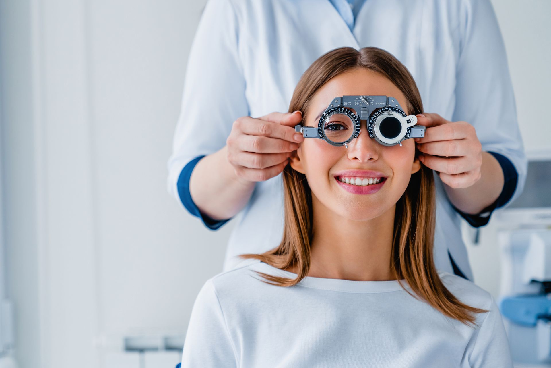 A smiling patient getting her vision checked by an eye doctor at an ophthalmological clinic.