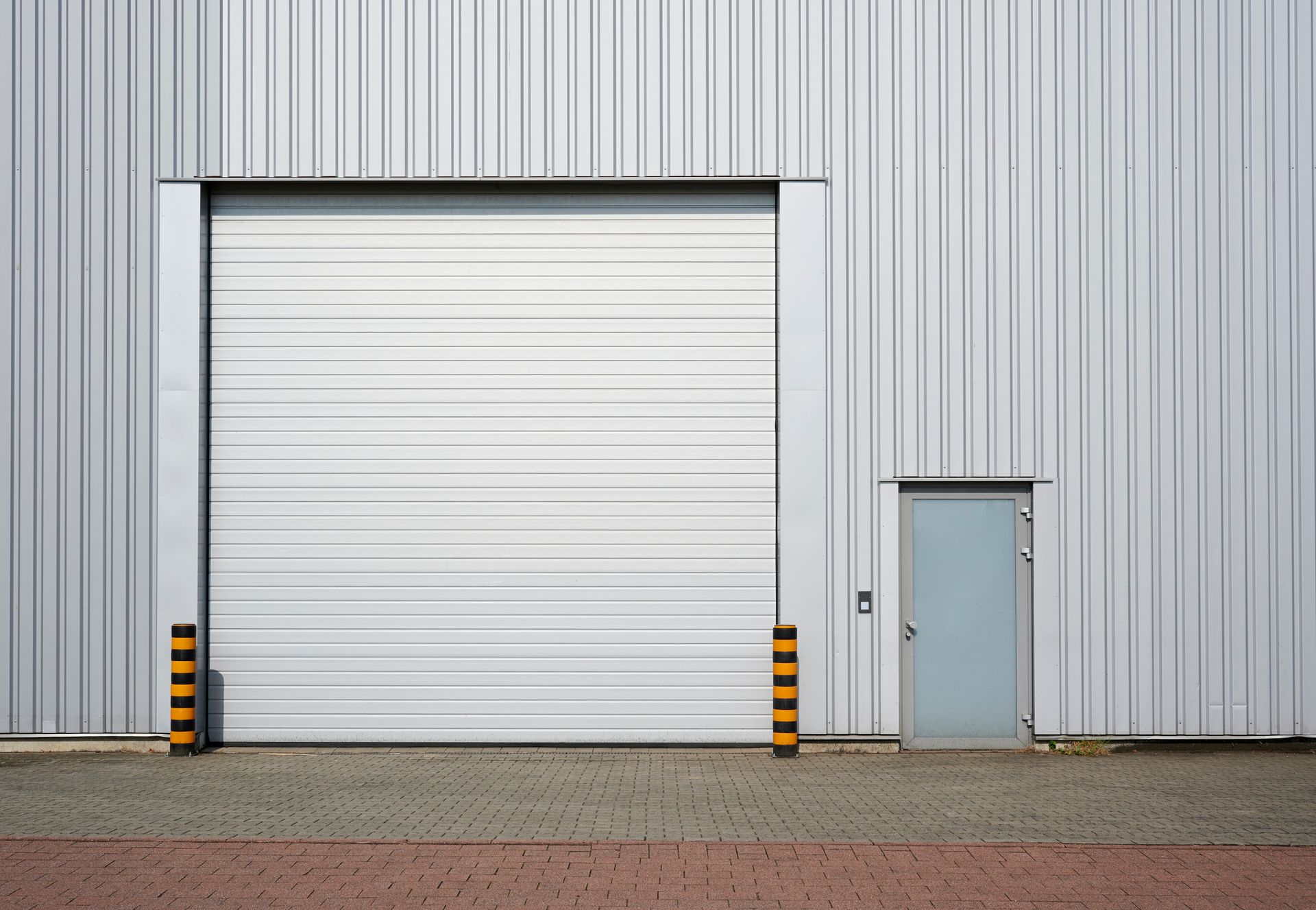 A white building with a large garage door and a small door.