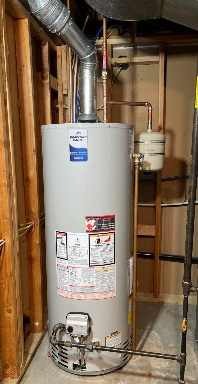 A water heater is sitting in a basement next to a ladder.
