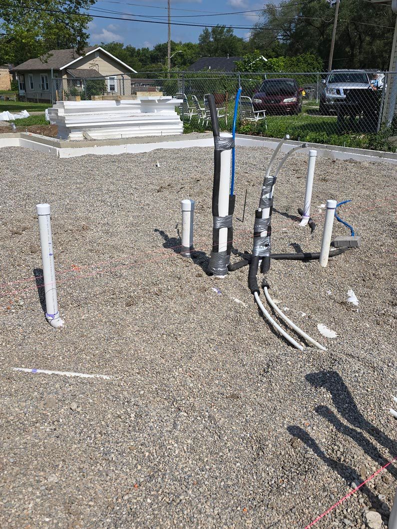 A bunch of pipes are sitting on top of a pile of gravel.