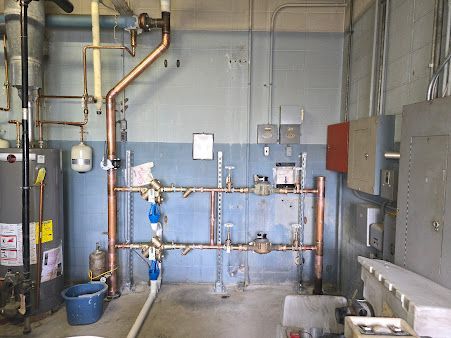 A room with a lot of pipes and a water heater