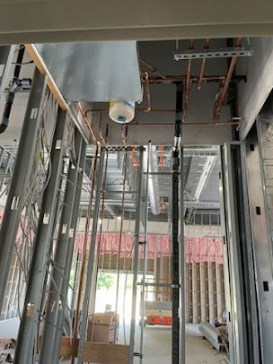 A building under construction with pipes hanging from the ceiling.