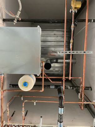 A bunch of copper pipes are hanging from the ceiling in a room.