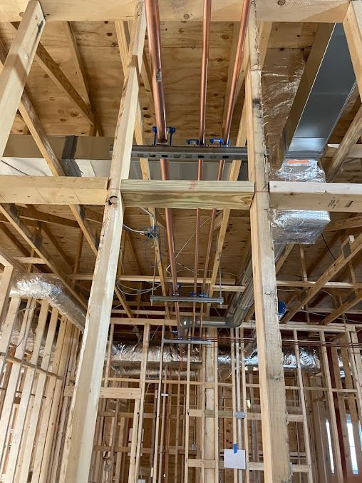 The inside of a building under construction with pipes coming out of the ceiling.