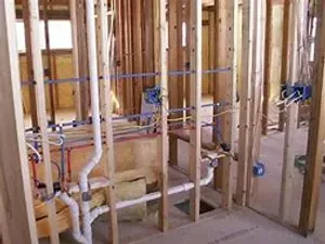 A bathroom under construction with a lot of pipes and wires.