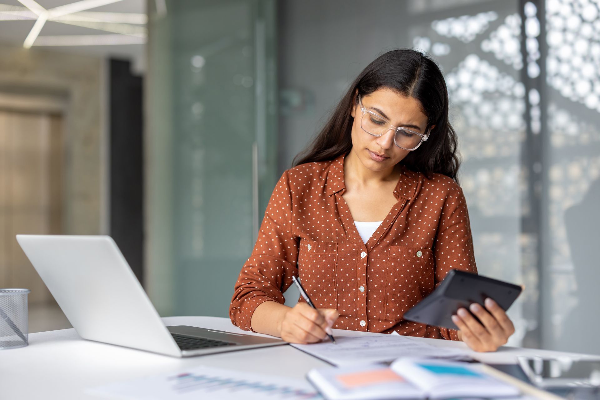 Young businesswoman calculating finances on a calculator.
