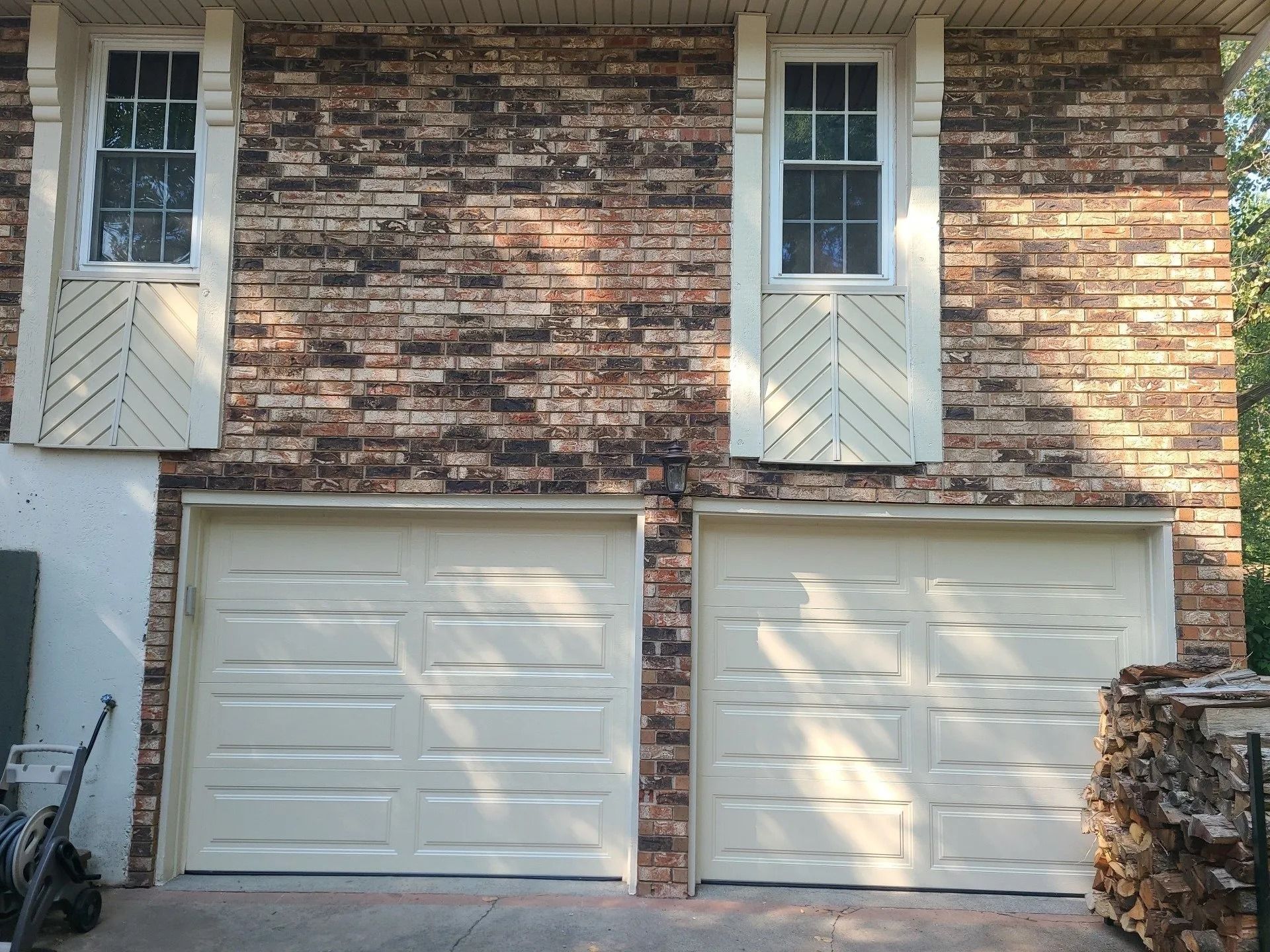 Brick house with two garage doors and windows above.