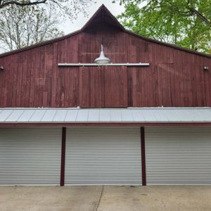 Red barn with silver corrugated garage doors.