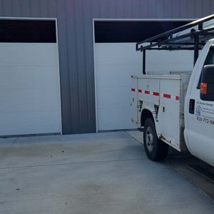 White garage doors with a work truck parked nearby.