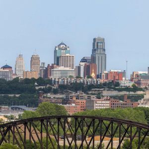 Kansas City skyline, with bridges and buildings, under a blue sky.
