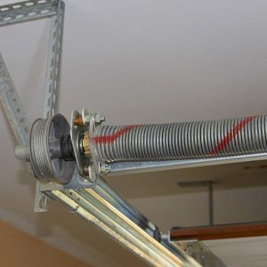 Garage door torsion spring, coiled, with red marking. Mounted on brackets.