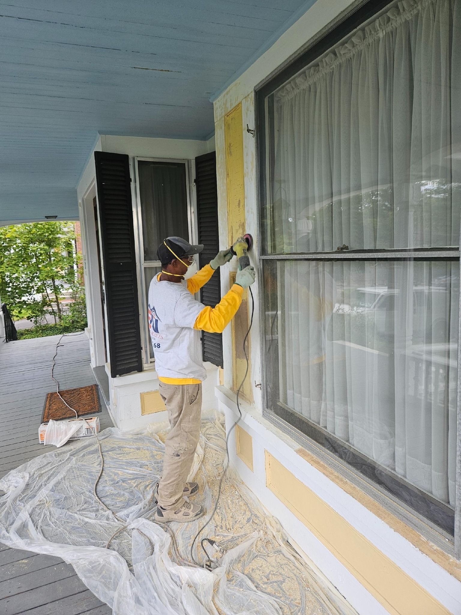 Person in red glove using a paint roller to apply gray paint to a white surface.