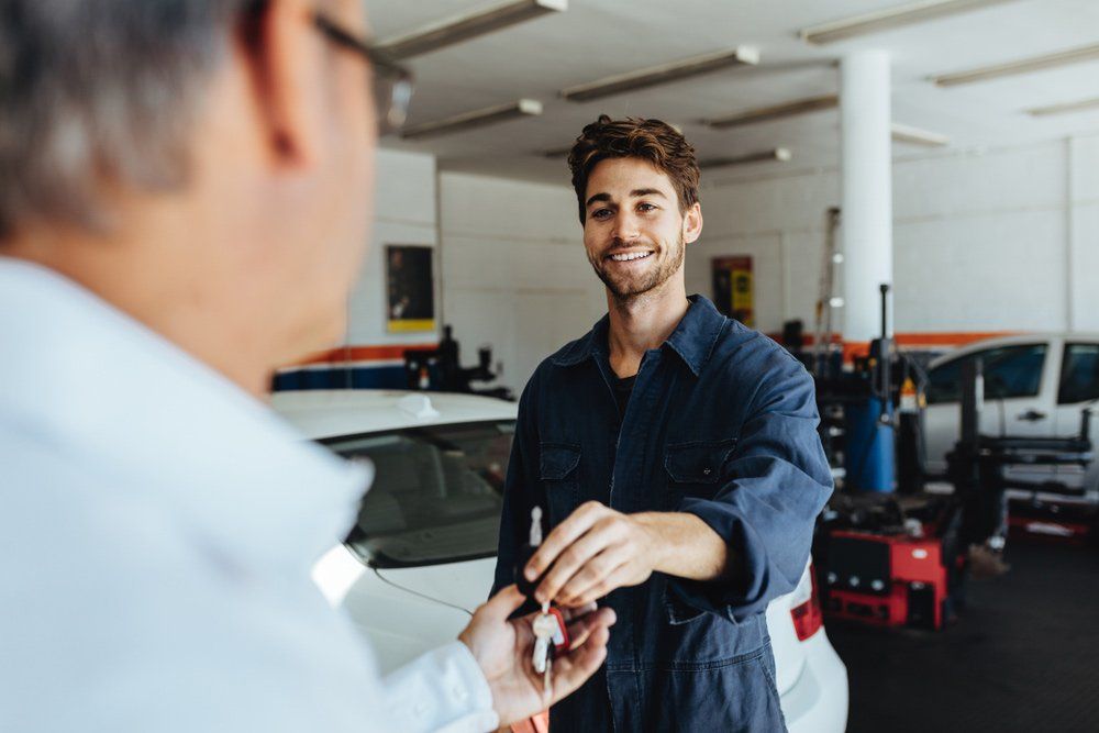 A Man is Giving a Car Key to a Mechanic in a Garage — SVS Auto Repairs & Dyno Tuning in Bungalow, QLD