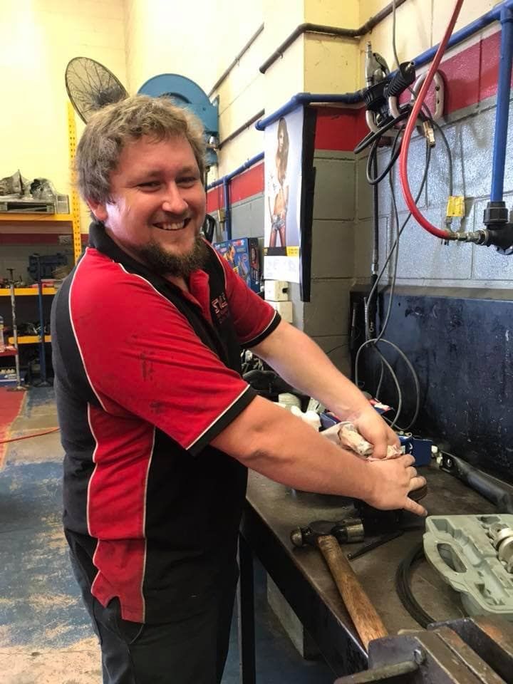 A Man in a Red and Black Shirt is Washing His Hands in a Garage — SVS Auto Repairs & Dyno Tuning in Bungalow, QLD