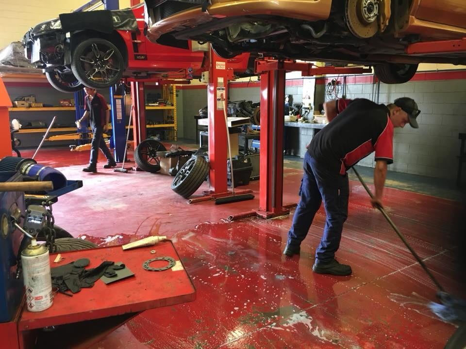 A Man is Cleaning the Floor of a Garage With a Mop — SVS Auto Repairs & Dyno Tuning in Cairns, QLD