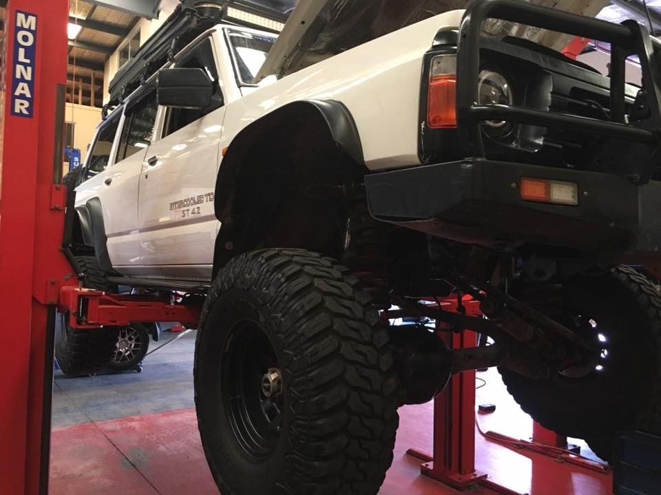 A White Truck is Sitting on a Lift in a Garage — SVS Auto Repairs & Dyno Tuning in Weipa, QLD