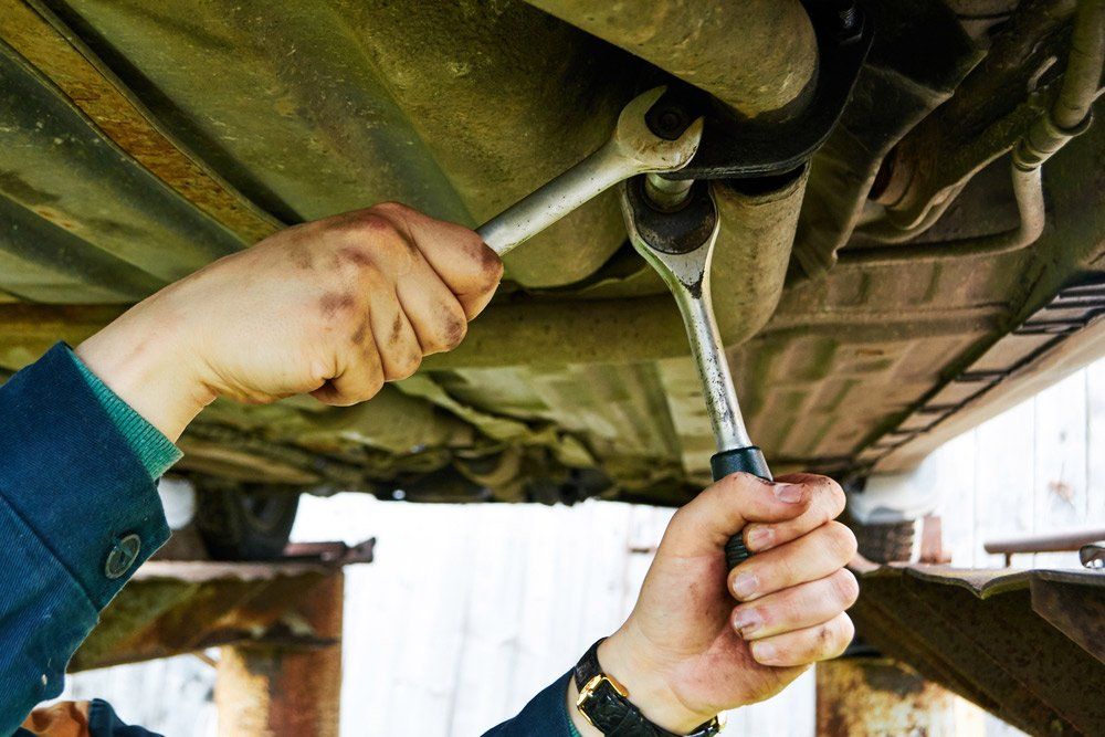 A Man is Working Under a Car With a Wrench — SVS Auto Repairs & Dyno Tuning in Bungalow, QLD