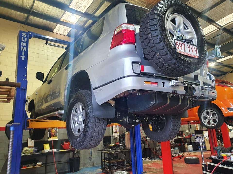 A Silver SUV is Sitting on a Lift in a Garage — SVS Auto Repairs & Dyno Tuning in Bungalow, QLD