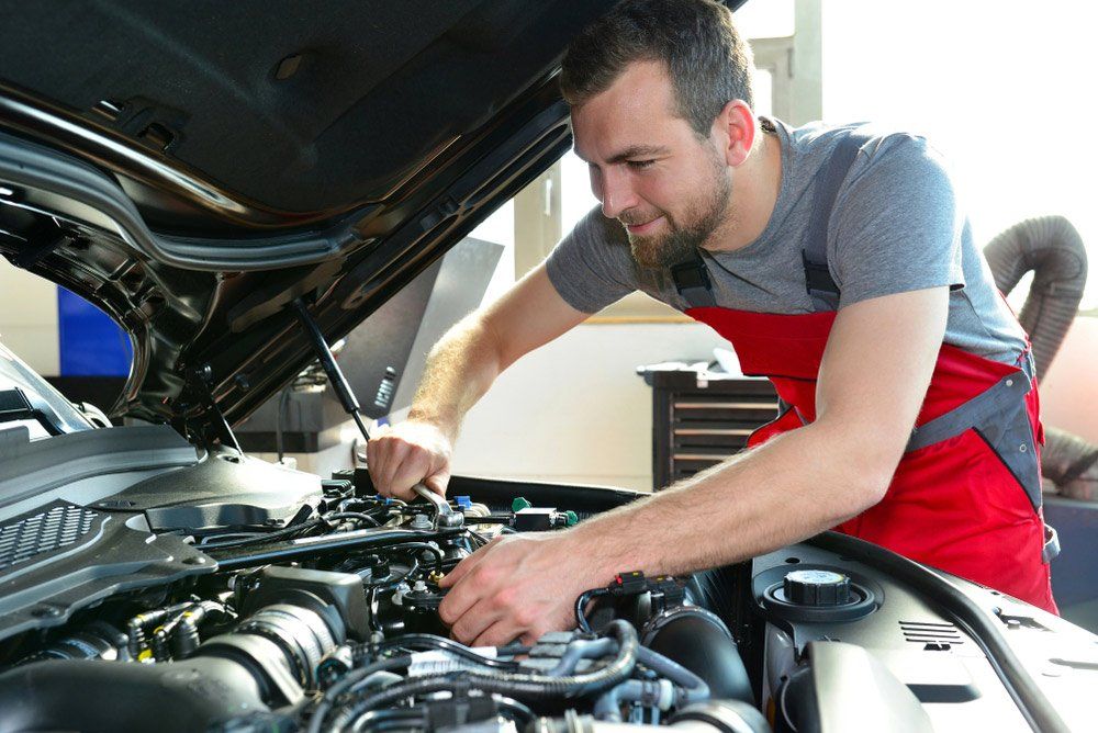 A Man is Working on the Engine of a Car With the Hood Open — SVS Auto Repairs & Dyno Tuning in Bungalow, QLD