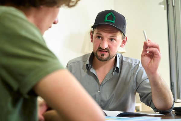 Ein Energieberater sitzt mit einem jungen Mann am Tisch und berät diesen zu Sanierungsmaßnahmen. 