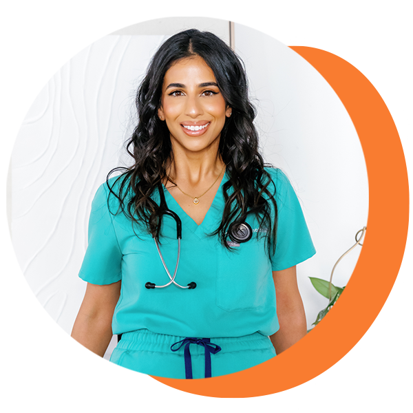 A woman in a green scrub top with a stethoscope around her neck is smiling.