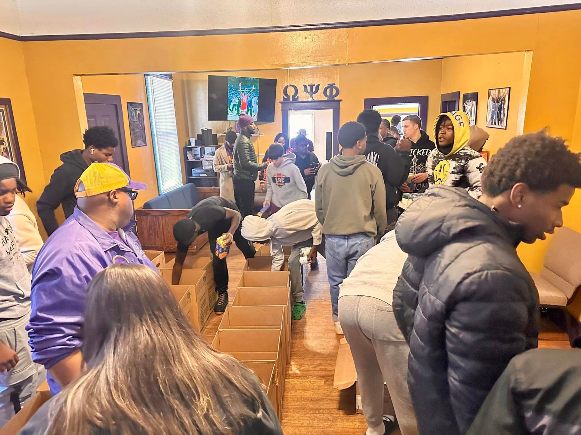 Group of people packing items into cardboard boxes indoors.