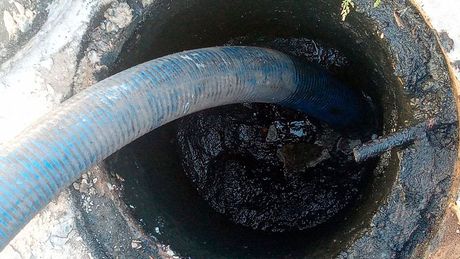 Uma mangueira está sendo usada para bombear água para um buraco no chão.