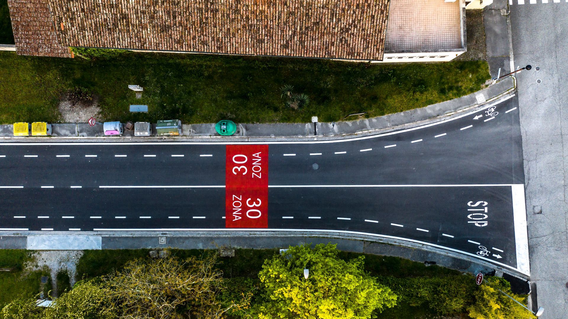 Vista dall'alto della strada con segnaletica orizzontale che indica il limite di velocità e segnale di stop.