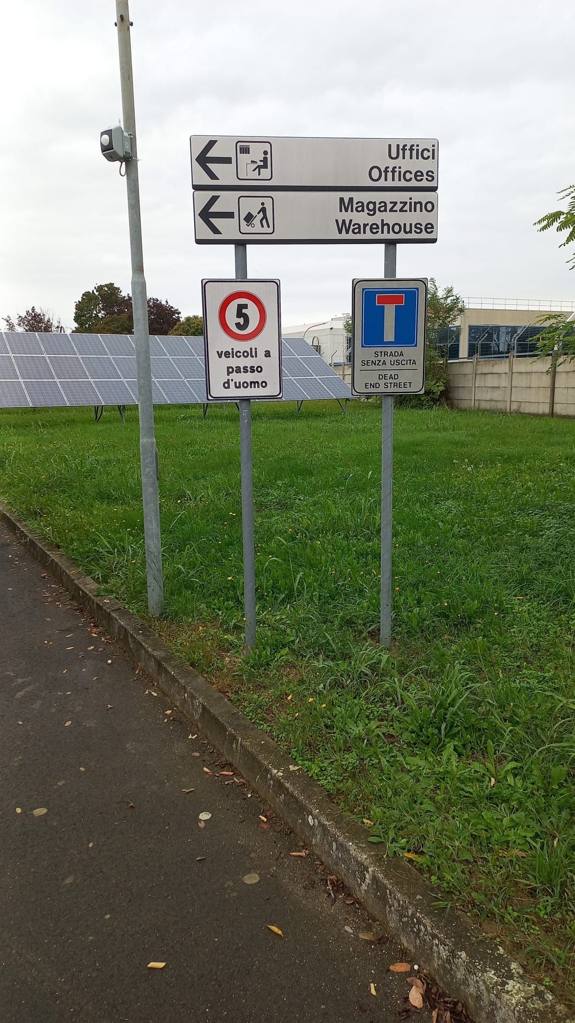 Cartelli che indicano le direzioni per gli uffici, i magazzini e il limite di velocità di 8 km/h; cartello di vicolo cieco.
