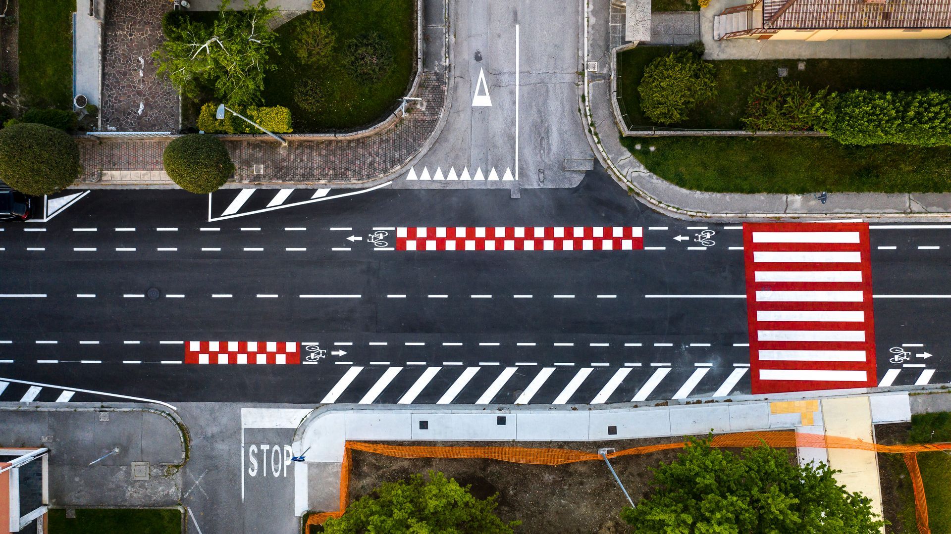 Incrocio stradale con attraversamento pedonale, piste ciclabili e dossi rallentatori contrassegnati in bianco, rosso e nero.