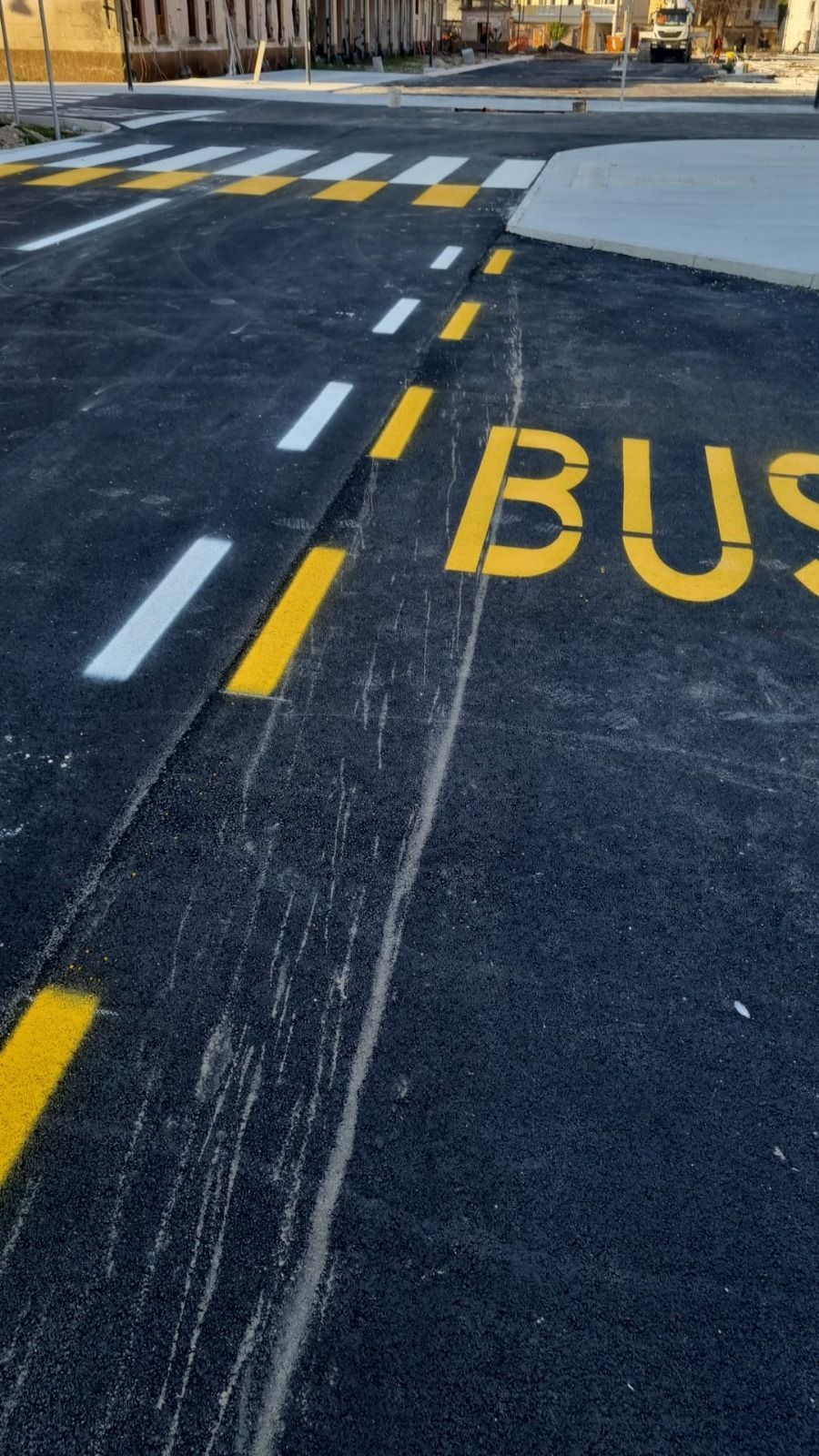 Segnaletica stradale: attraversamento pedonale bianco, corsia gialla per gli autobus, linee tratteggiate. 