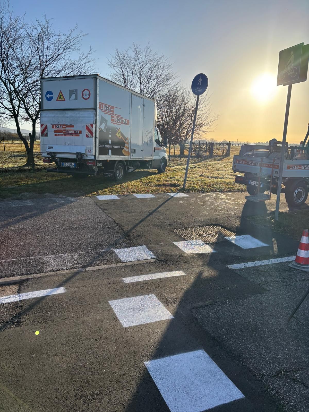 Attraversamento pedonale ridipinto, con un camion e un veicolo da lavoro su entrambi i lati. 